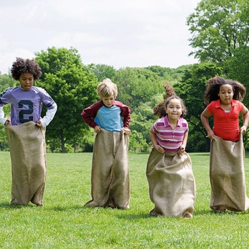 kids playing outdoors with a sacks - sack race
