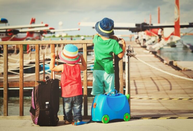 this is an image of 2 kids with luggage looking out at the airport 