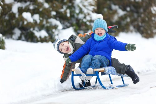 2 kids playing on a sled