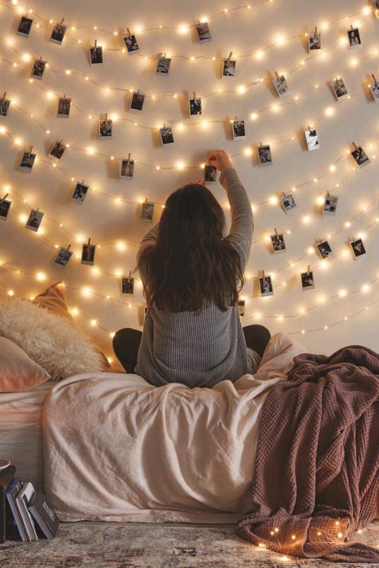 A girl attaching pictures to a photo clip LED string lights.