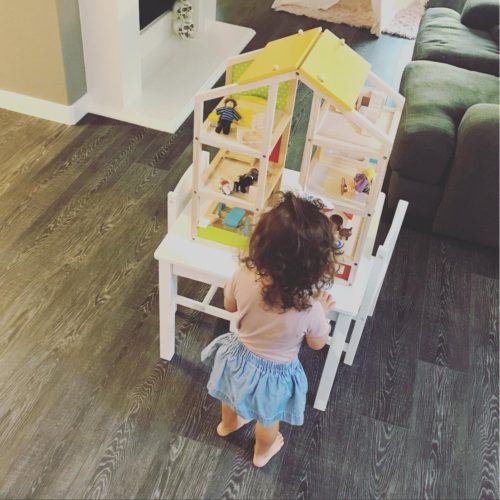 todler girl playing with a dollhouse on table