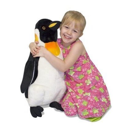 This is an image of a little girl hugging a giant plush penguin. 