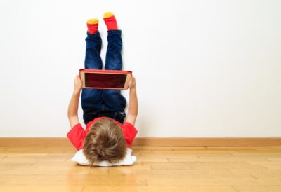 This is an image of a boy Kid using a tablet upside down 