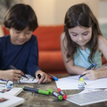 2 kids drawing and using a coding toys
