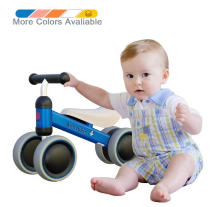 This is an image of an infant holding a pedal less toy vehicle. 