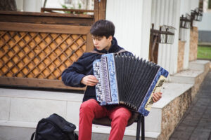 this is an image of a young man playing the accordion on the street