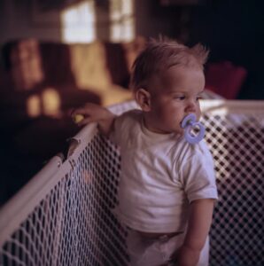 this is an image of a toddler standing in a playpen