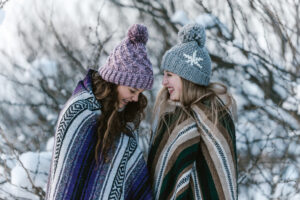 this is an image of two women outside wearing blankets and wooly hats