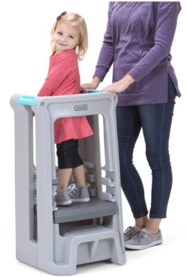 this is an image of a toddler inside a gray tower stel stool with 3 adjustable heights..