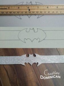 batman band for wrists laying on a wooden floor next to a ruler