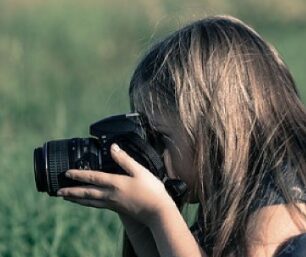 This is an image of a little girl using camera 