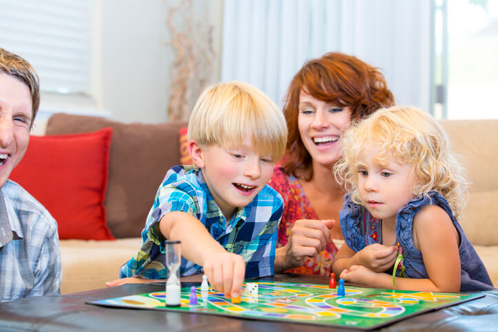 Family with two little kids having fun playing board games. 