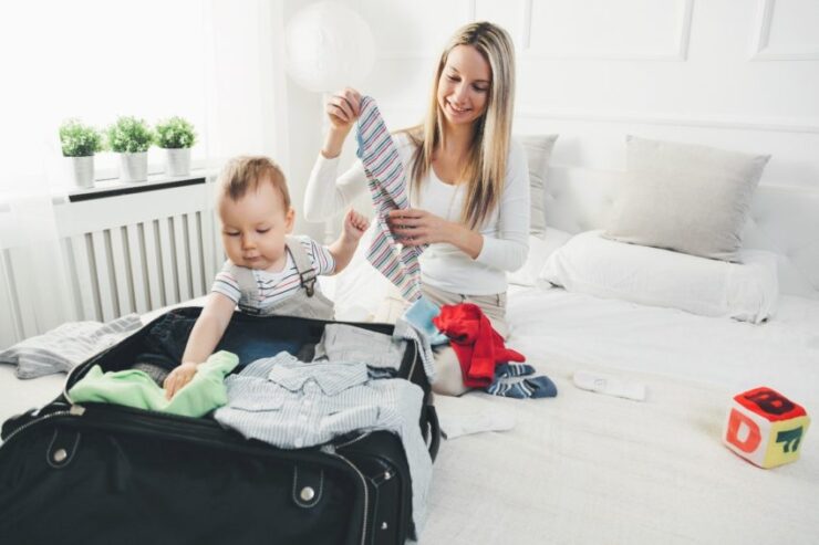 this is an image of infant and mother on the bed packing a suitcase 