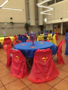 large room with table and chairs covered in different superhero capes