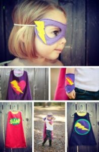 little girl dressed up in a superhero costume and mask