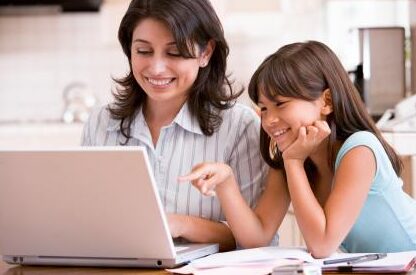 This is an image of a mom showing her kid how to use a computer