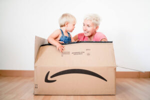 Mother unpacking cute blond toddler from big Amazon Prime box