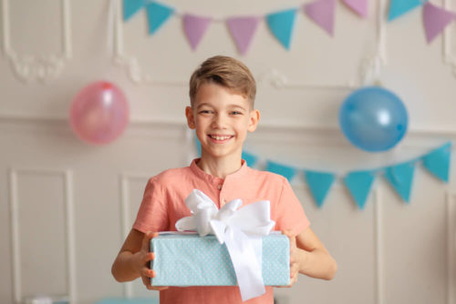 Happy Birthday Portrait of a happy cute boy of 8 years old in a festive decor with confetti and gifts.
