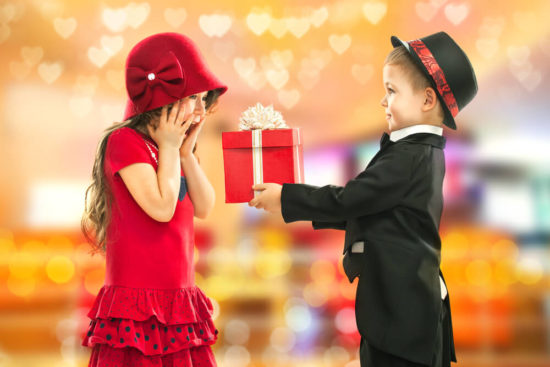 little boy giving a present to a little girl on valentines day
