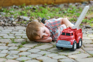 this is an image of a young boy playing with a toy fire truck