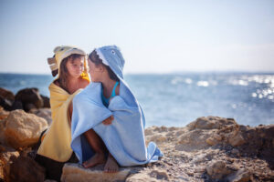 Two sisters playing on the beach, beach towels , sea, sun, warmth and comfort .