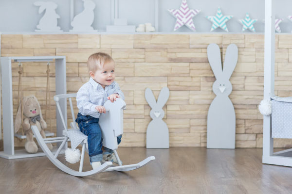 Cheerful boy Toddler baby swinging on a rocking chair in the shape of a horse.