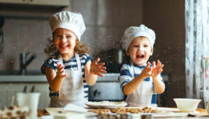 happy family. 2 young kids are preparing the dough, bake cookies in the kitchen with baking set