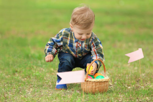 Cute little boy with basket on green grass. Easter egg hunt concept