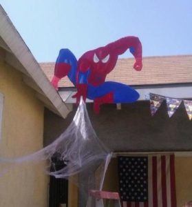 spiderman image hanging over the gutter of a house with web coming down the side of the buidling