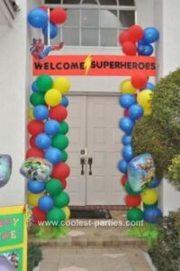 superhero entrance banner at the entrance to a house with balloons surrounding the banner