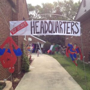 superhero entrance banner at the entrance to a house with different superheros at each point leading down the path