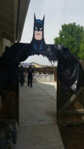 superhero entrance door with a batman head peering on top of the door frame and black plastic eaither side of the door like a batman cape