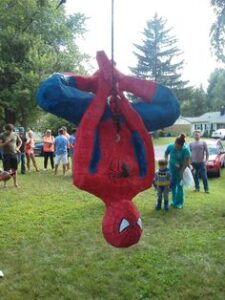 superhero pinata game with a spider man hanging as a pinata and kids surrounding it 