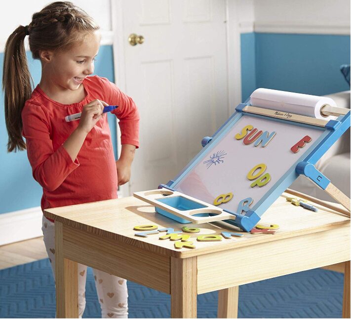 this is an image of a girl playing with an art easel on a table