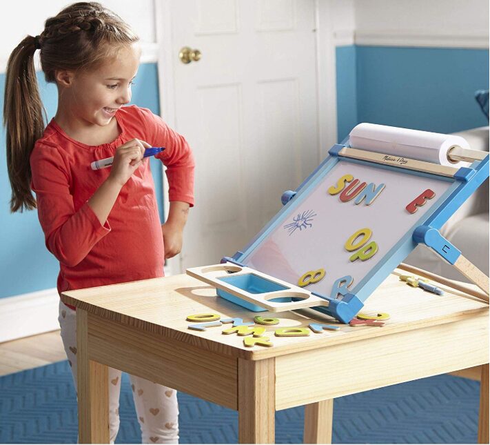 this is an image of a girl playing with an art easel on a table